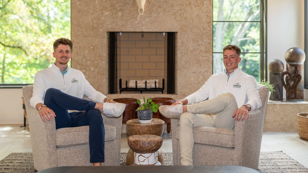 Ned and Luke Morrison seated in two armchairs in front of a stone fireplace