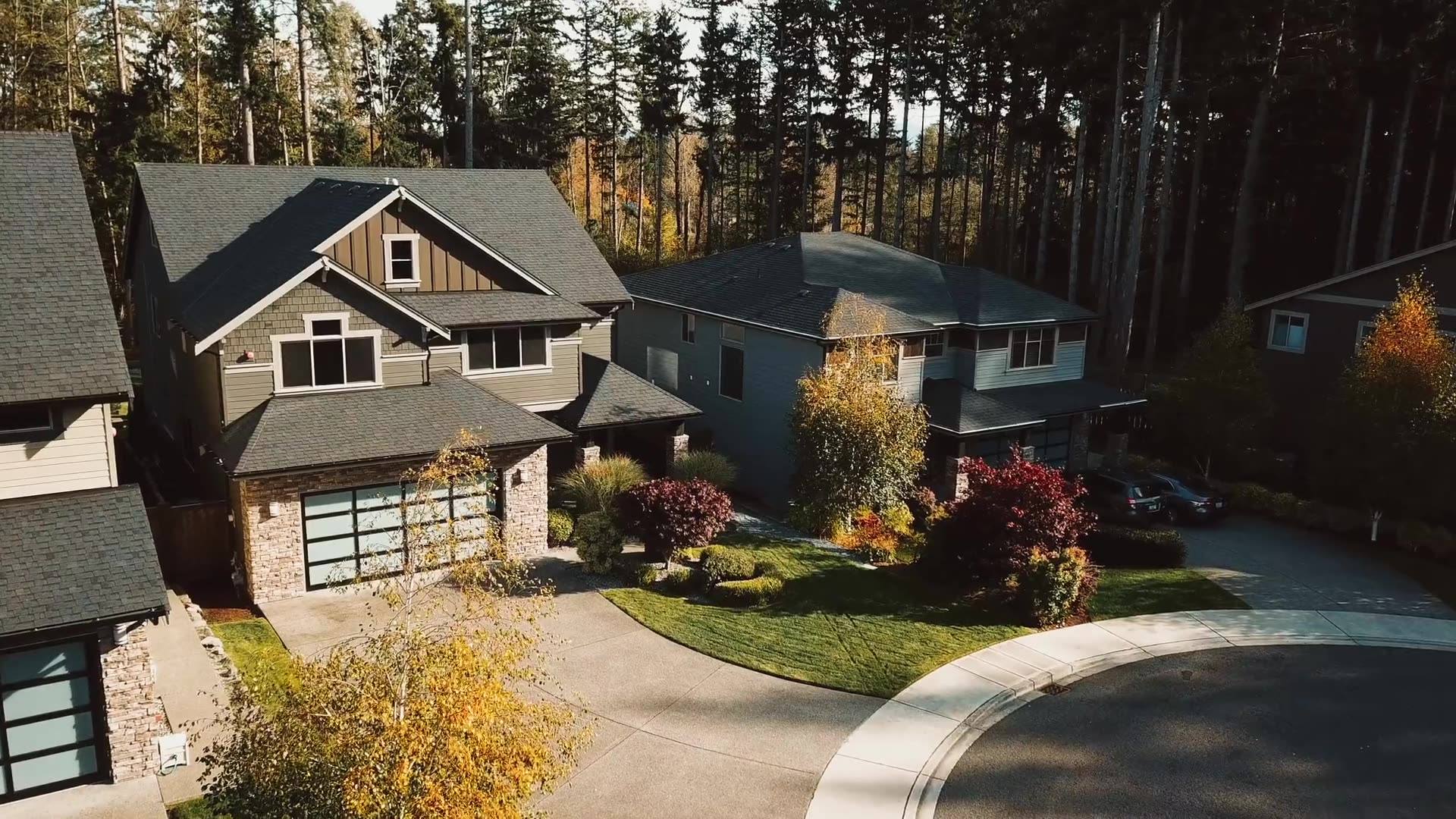 An aerial view of family homes around a cul-de-sac in autumn, lawns and beds neatly kept