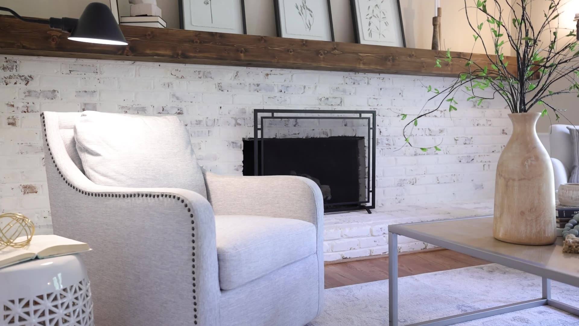 A quiet sitting room with a fireplace and framed prints above a wooden mantel